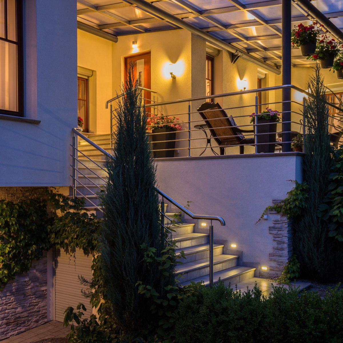 a brightly lit exterior of a home in the evening with lights installed outside windows, doors, and on stairs