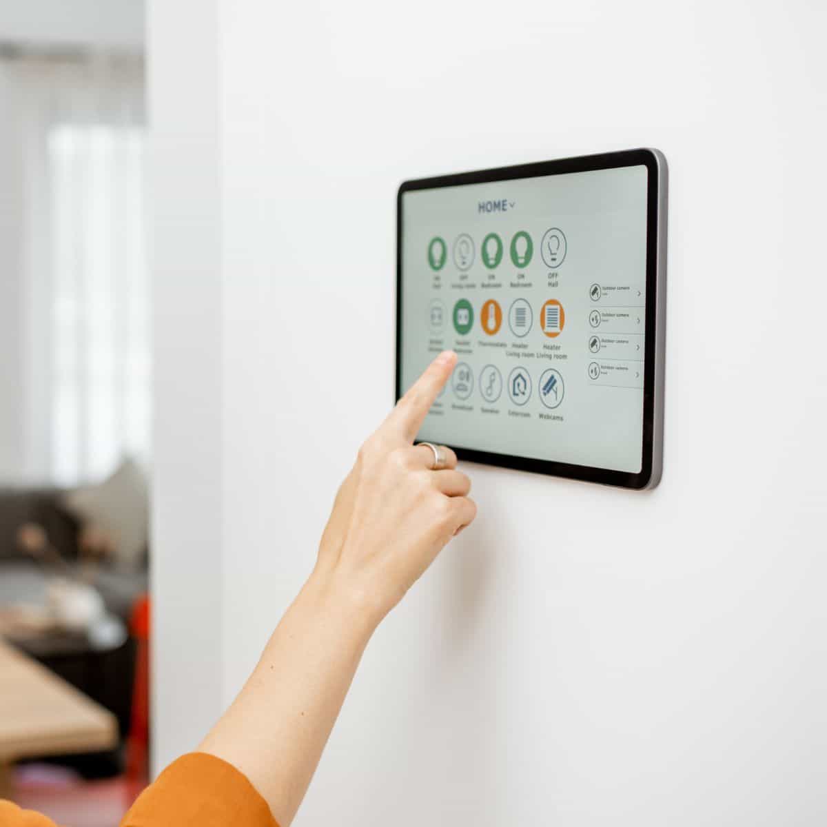 woman smiling while using a digital smart screen mounted on her living room wall to control her home